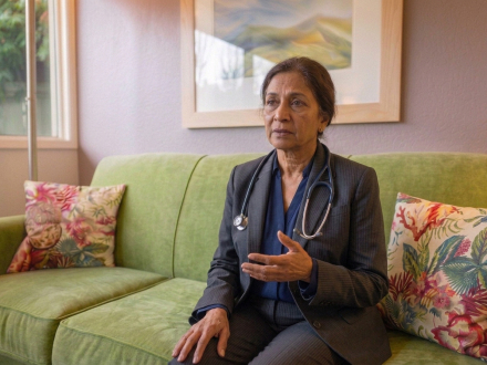 Woman wearing a stethoscope, sitting on a couch during a conversation